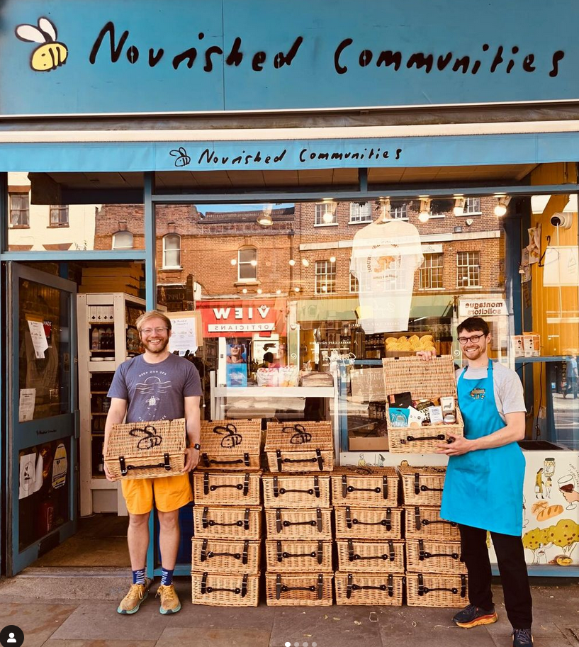 The owners of Nourished Communities, Rollo and Roland, standing with hampers outside their shop in Islington, North London. 