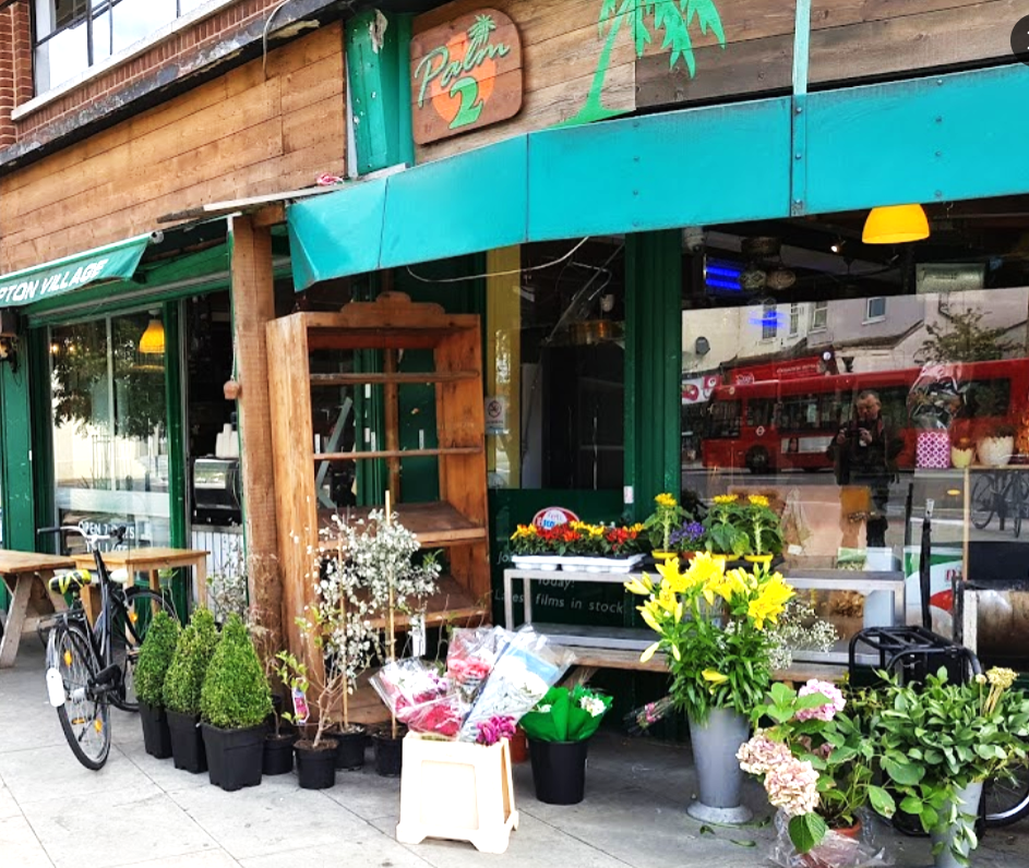 Flowers and other plants outside the shopfront of Palm 2 Deli in Clapton.